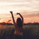 woman waving her hands during golden hour